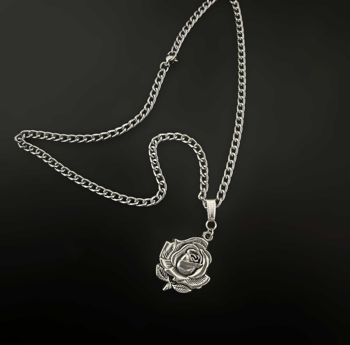 Gothic Rose Cross laid flat. Silver, heavy rose flower motif charm on a thick curb chain for lovers of grunge, alt, and gothic jewelry and fashion across India.