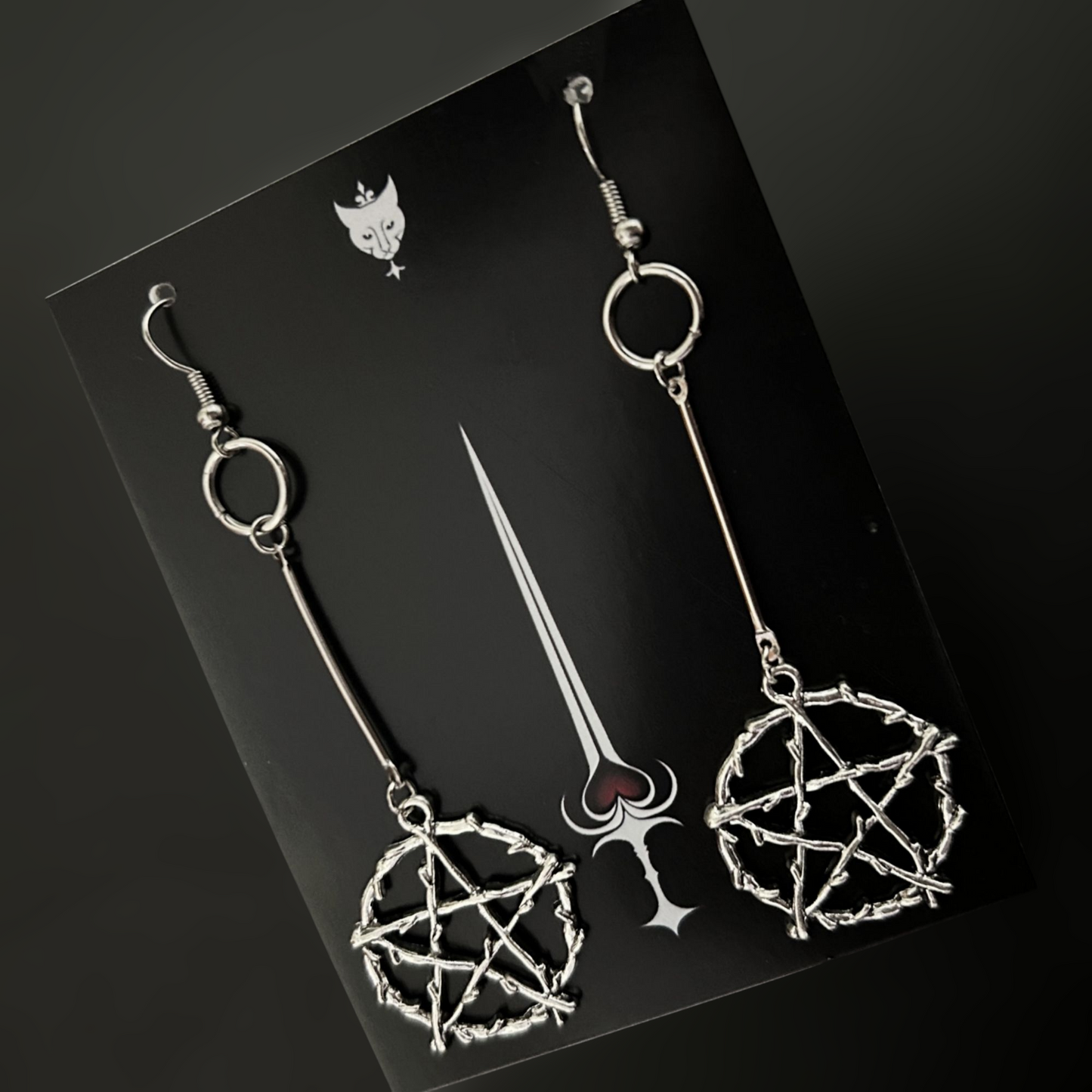 Flat lay of Daedra’s Mark Drop Earrings on Phantom Cat card, silver bone pentagram gothic jewelry for alt, witchcore, and fantasy fashion. Shop India now.