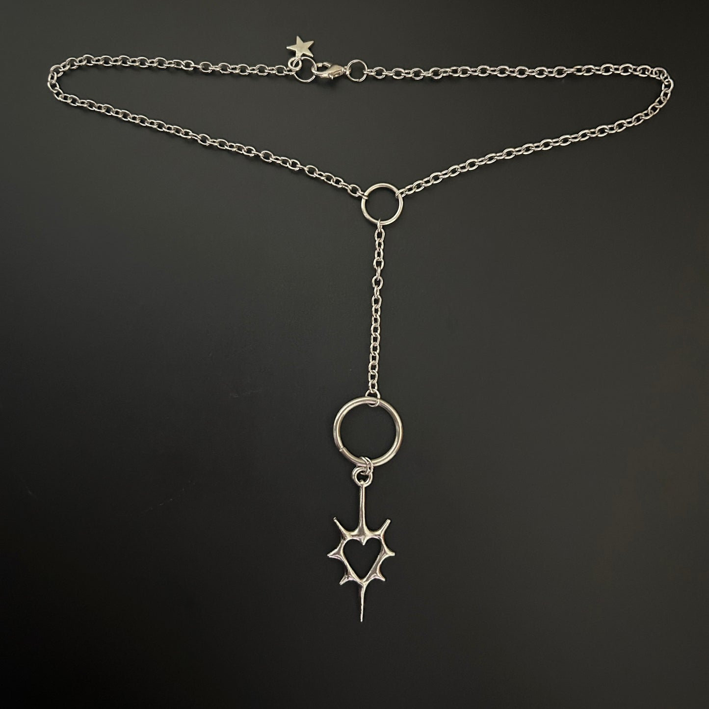 Y-drop silver necklace feat. a gothic spiked heart pendant with oversized rings, laid flat. Tarnish-resistant alt jewelry ideal for gothic fashion, anime cosplay, and grunge-inspired K-pop styling.