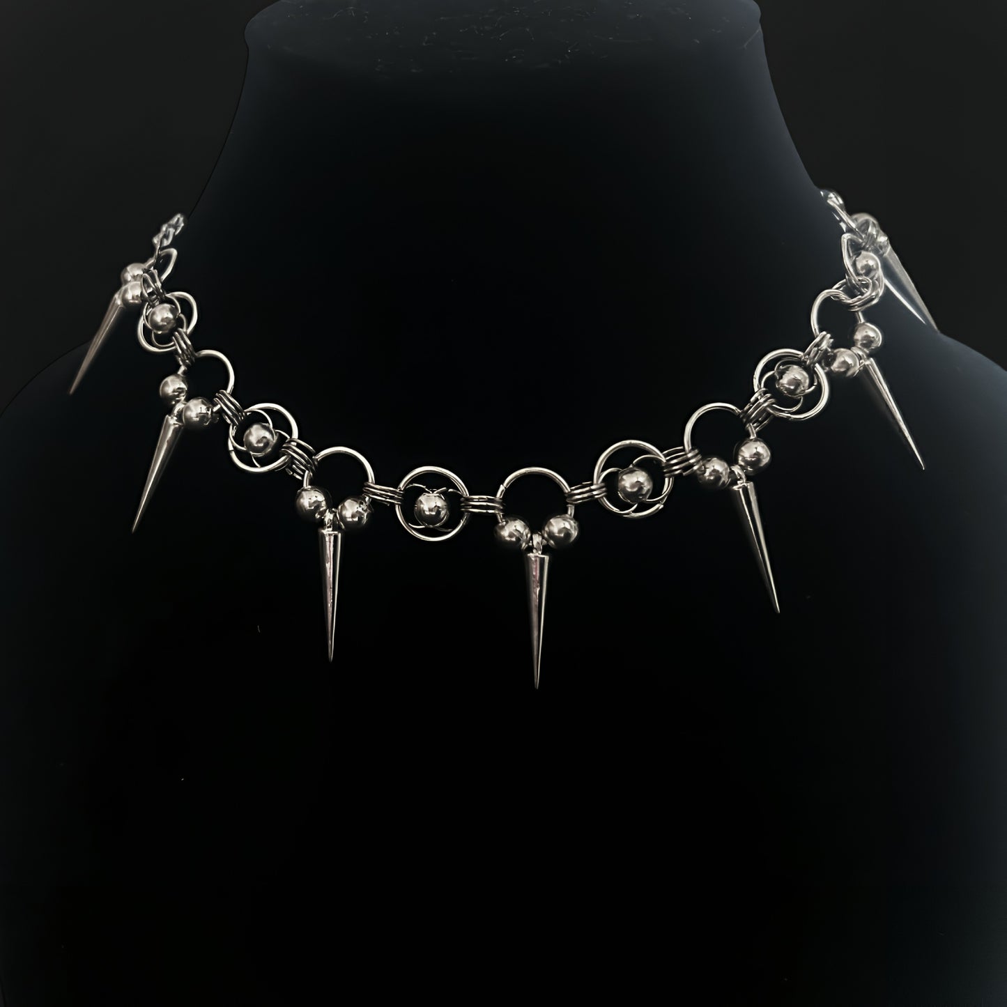 Close-up of gothic chainmail choker necklace with chainmaille rings, polished silver beads and cone spikes. Shop grunge and alt jewelry with an industrial edge in India