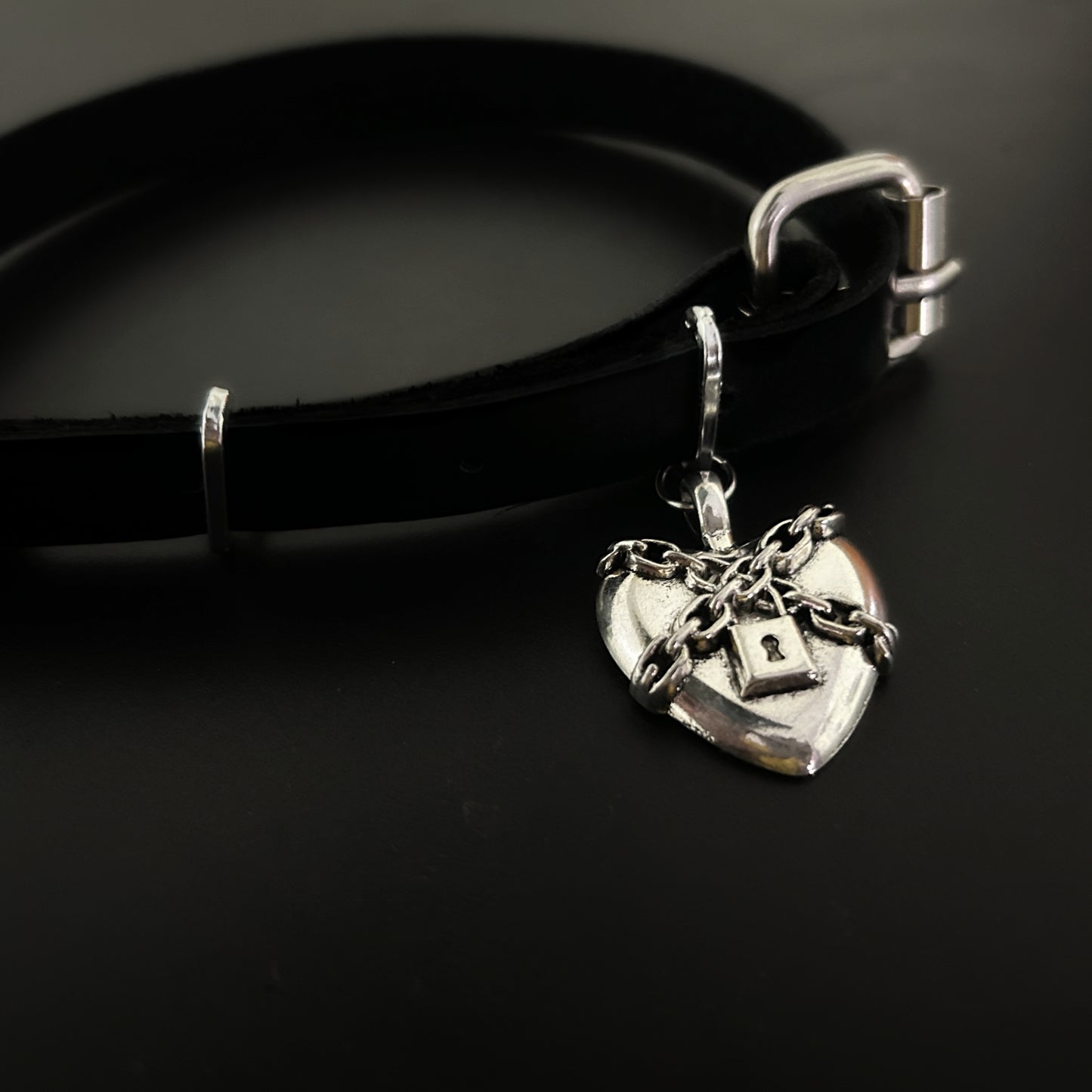 Flat lay of chained heart leather choker with soft leather strap. Handmade gothic jewelry India. Alt and punk fashion accessories for y2k and anime cosplay lovers.