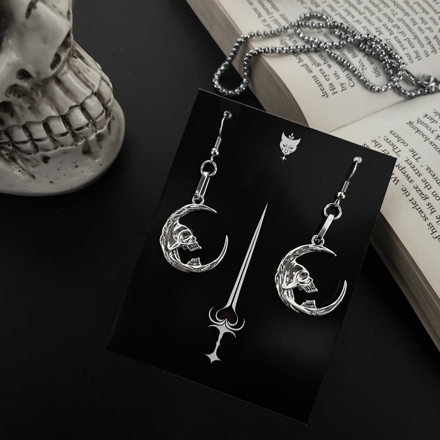 Fantasy skull earrings by Phantom Cat featuring occult-inspired crescent moon shapes. Gothic alt accessories for lovers of y2k and anime cosplay fashion. Made in India.