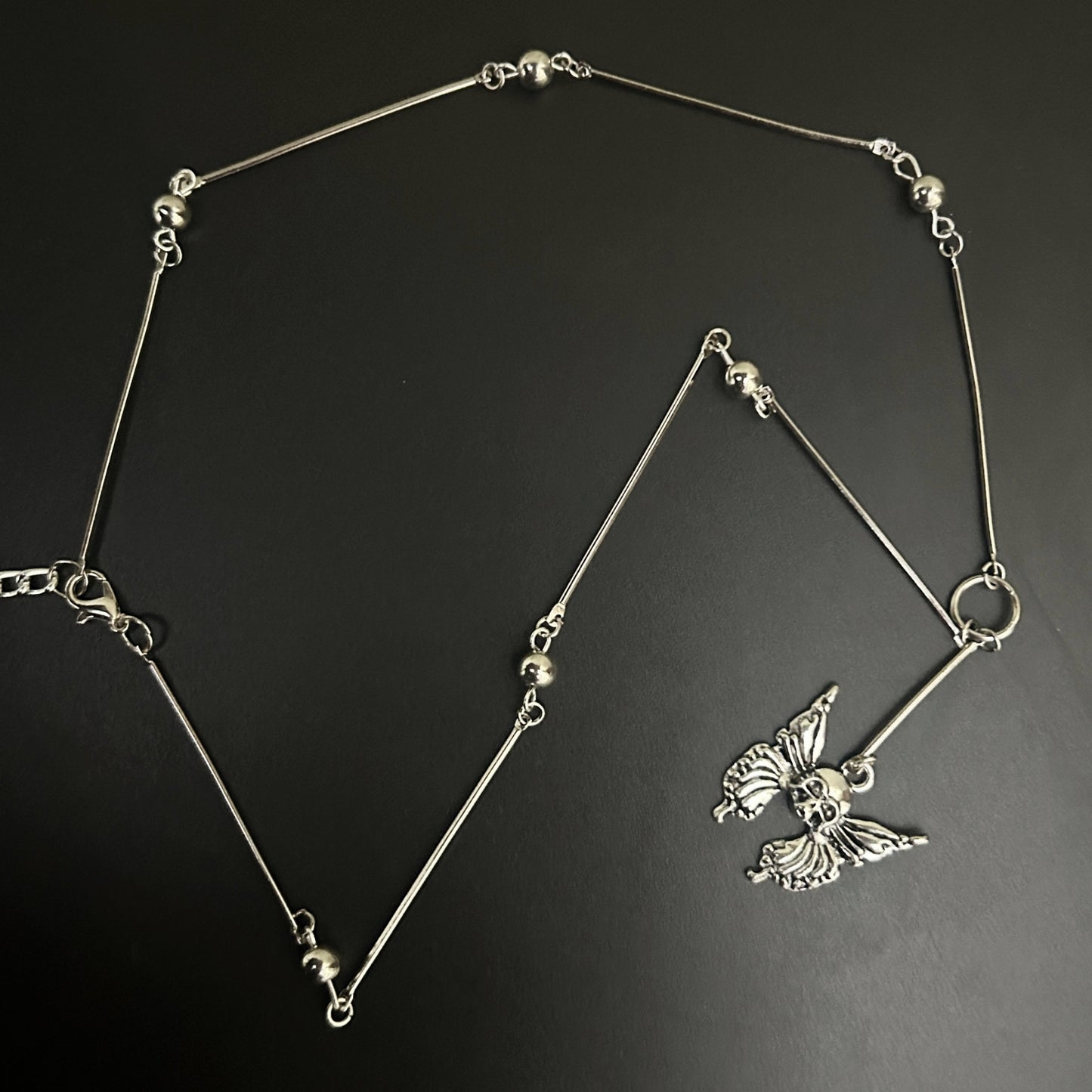 Full flat lay of Grunge Necklace feat. spine link chain with chrome beads and a gothic butterfly skull pendant. Shop gothic jewelry designs for alt, y2k and cosplay aesthetics in India