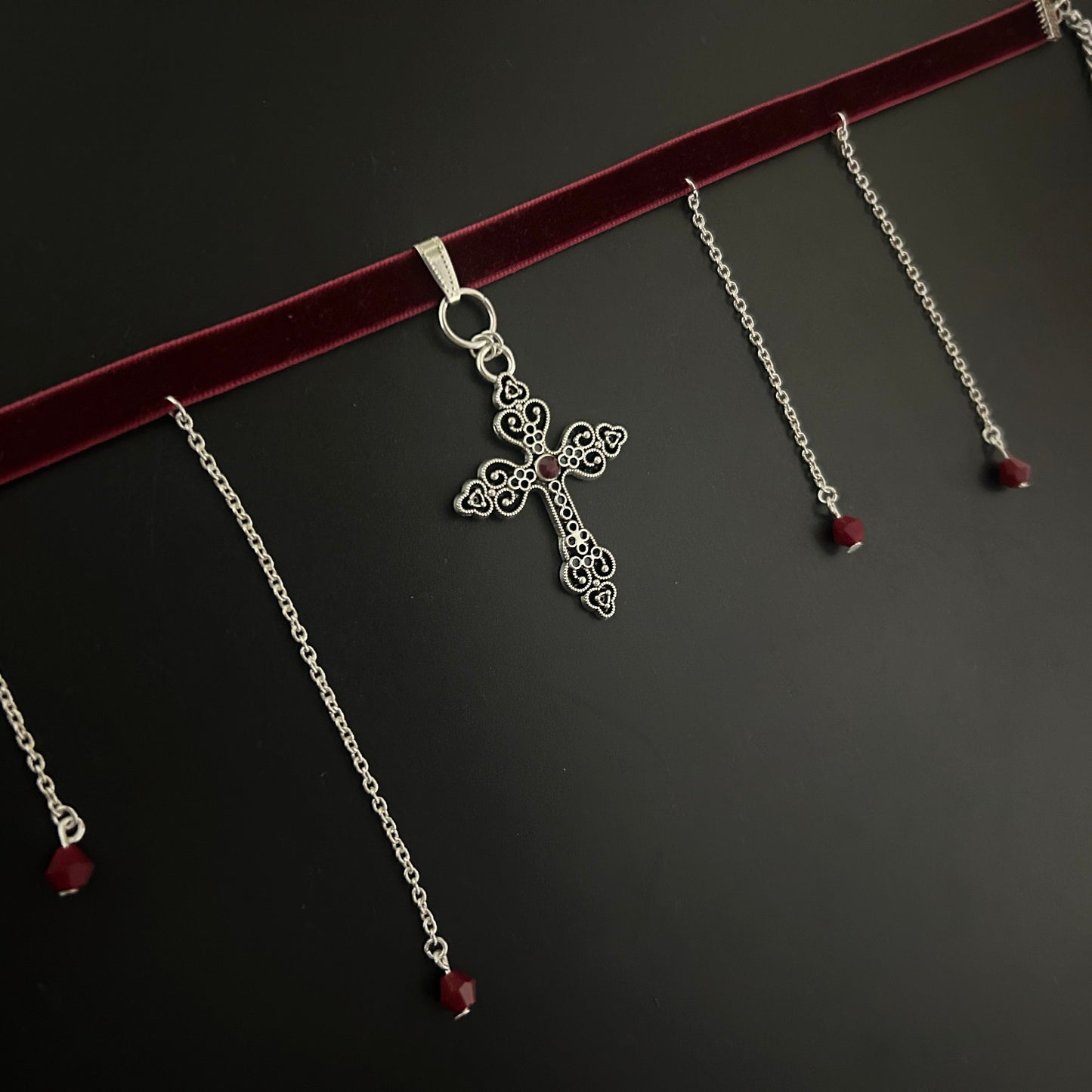 Flatlay of maroon velvet gothic choker with detailed silver cross and hanging chain accents – gothic jewelry, fantasy style, y2k alternative look