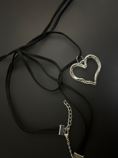Flat lay of black nylon string choker with silver heart pendant and extender chain. Lightweight adjustable alt fashion piece. Phantom Cat India.