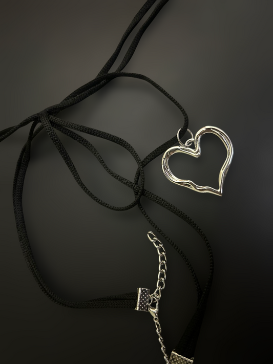 Flat lay of black nylon string choker with silver heart pendant and extender chain. Lightweight adjustable alt fashion piece. Phantom Cat India.