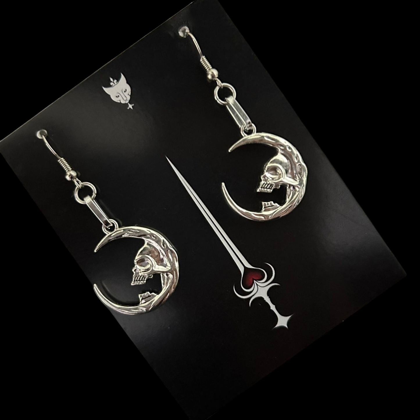 Silver skull moon earrings for dark fantasy styling - displayed on Phantom Cat Jewelry Card. Gothic vampire-core jewelry made for alt wardrobes. Shop unisex grunge accessories online. 