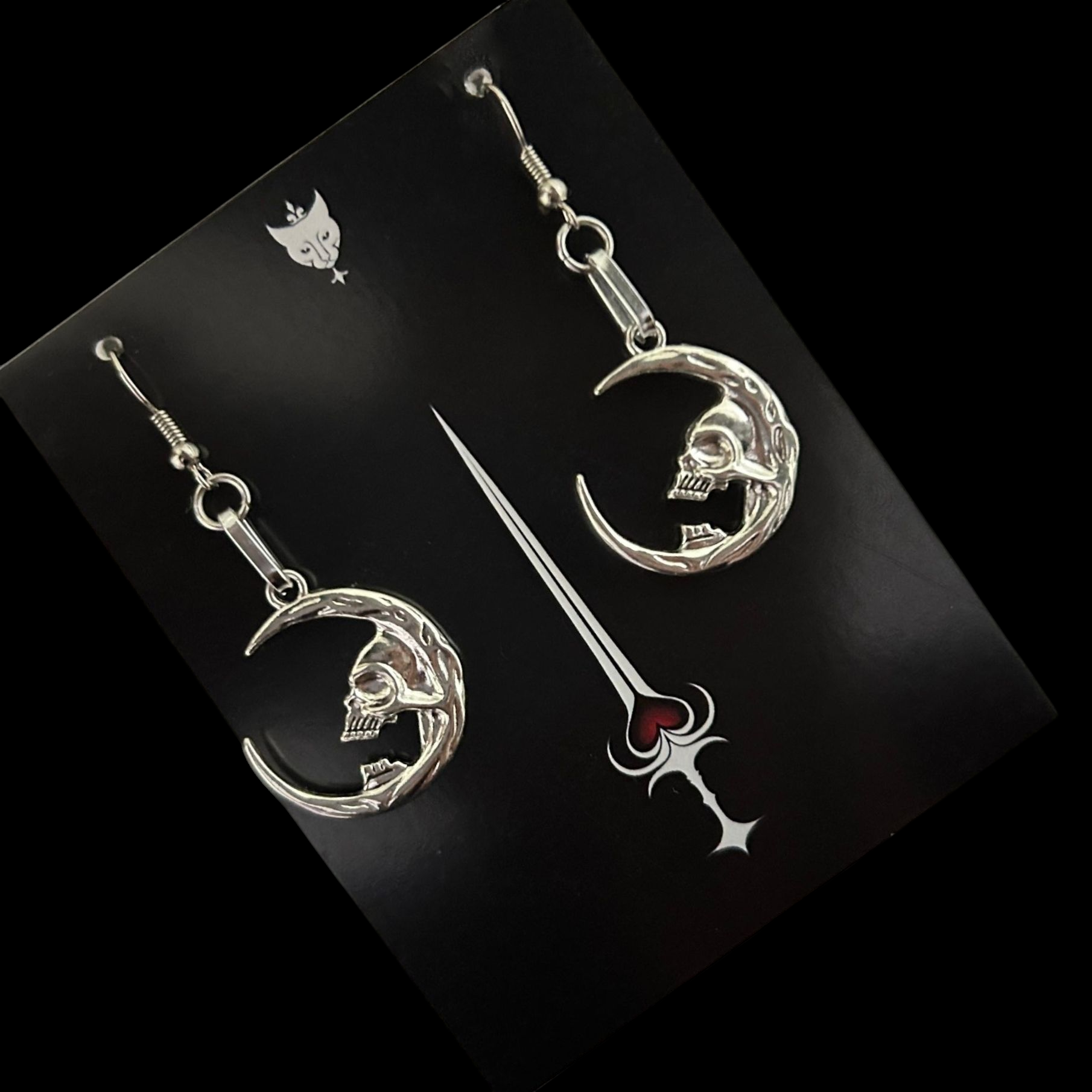 Silver skull moon earrings for dark fantasy styling - displayed on Phantom Cat Jewelry Card. Gothic vampire-core jewelry made for alt wardrobes. Shop unisex grunge accessories online. 