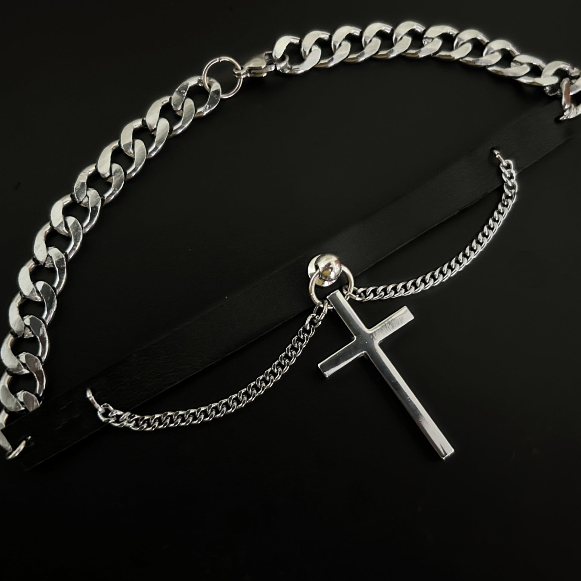 Overhead view of black leather punk rock-themed choker with large cross charm and silver chain. Stainless steel collar. Perfect for lovers of alt, grunge and y2k fashion across India. 