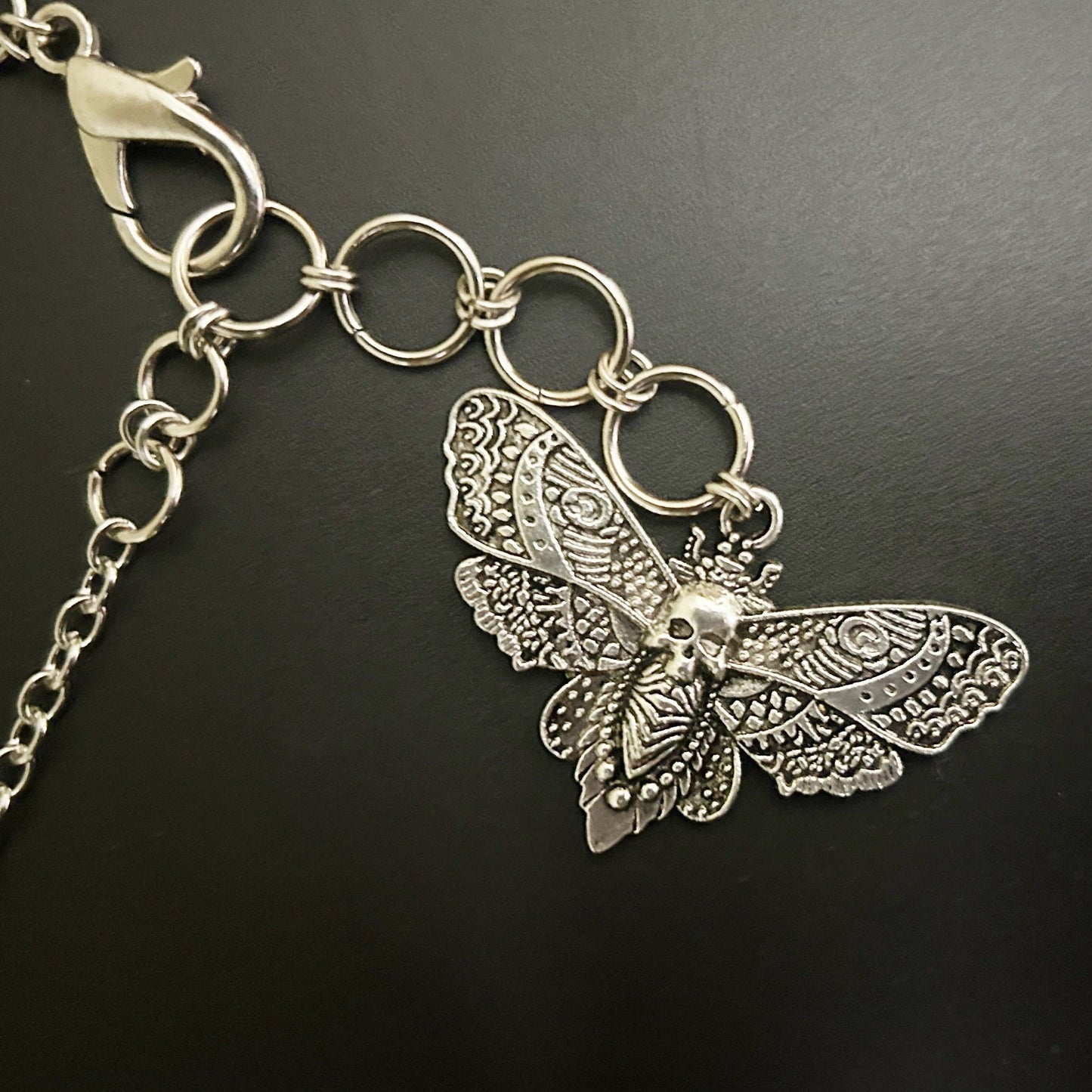 Close-up view of detailed skull moth pendant with intricate wing engravings — a gothic accessory for alt-core, fantasy, and anime cosplay fashion in India