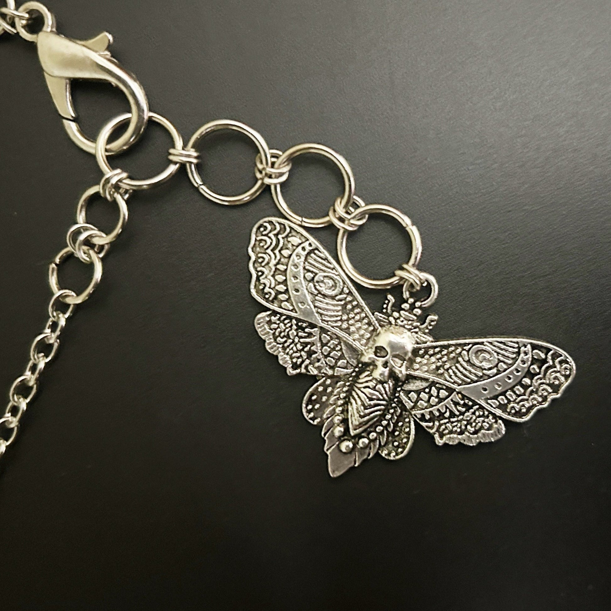 Close-up view of detailed skull moth pendant with intricate wing engravings — a gothic accessory for alt-core, fantasy, and anime cosplay fashion in India