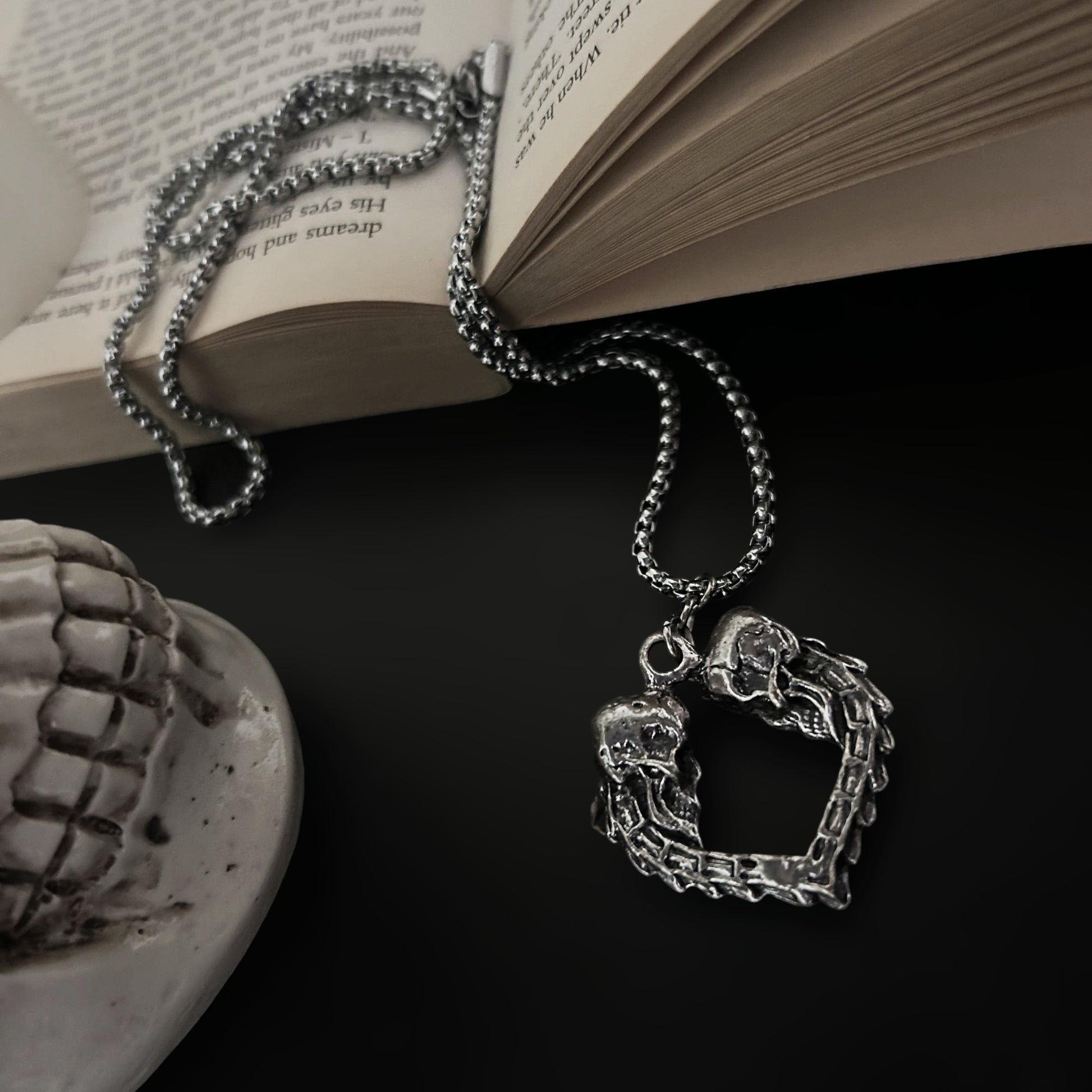 Cinematic view of gothic pendant by Phantom Cat India - Old ancient tome with a real skull - ambient goth setting for dark, whimsical jewelry and accessories online. Shop India. 