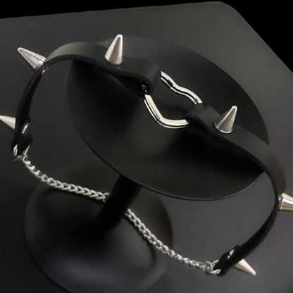 Flat lay of spiked leather choker with stainless steel heart, displayed on a black circular stand. Conical metal spikes. Ideal for gothic, punk, grunge, and alt fashion styling in India